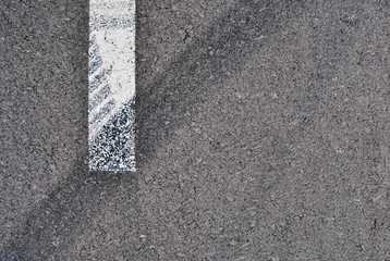 Asphalt texture with white line and tire marks . Top view