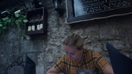 Fototapeta na wymiar Beautiful girl, in an open Italian restaurant, in old town, the menu will choose a dish