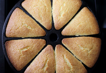 Fresh cornbread from the oven baked in a cast iron wedge pan, resting on top of the stove.