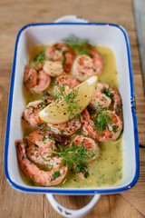 Lemon garlic butter shrimp on light wooden background