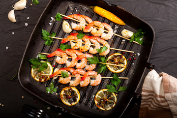 Prawns Shrimps roasted on pan with lemon, garlic and herbs on black background. Top view.