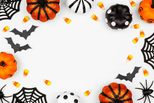 Halloween frame of pumpkins, candy and decor. Flat lay over a white background with copy space.