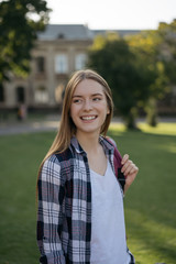 Portrait of happy student with backpack walking to university. Education concept. Cheerful woman with happy emotional face waiting for taxi outdoors 