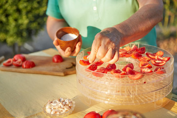 Woman in the garden sprinkle tomatoes with salt