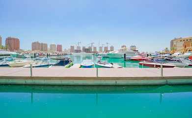 Fototapeta na wymiar Pearl-Qatar at Doha marina with signs of on-going city growth in distance with construction cranes on horizon