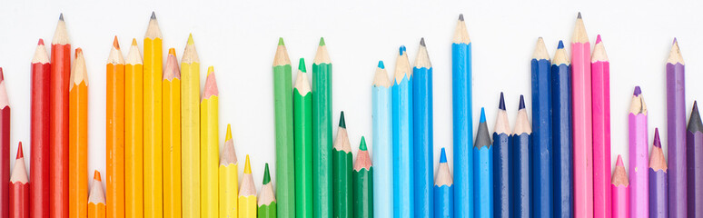 Panoramic shot of line of different sizes color pencils isolated on white