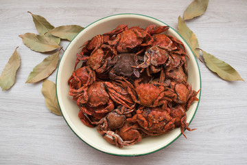 blue crabs cooked in a plate on a wooden table and bay leaves