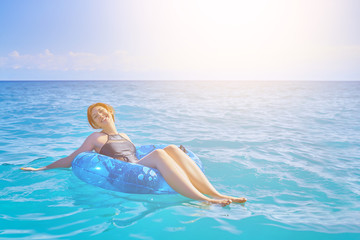 Beautiful young woman relax on inflatable ring in sea water