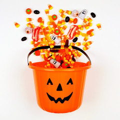 Halloween Jack o Lantern pail with spilling candy, above view on a white background