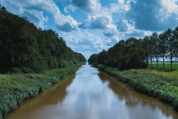 Fototapeta na wymiar Kanal in Holland mit Wald und Wolken