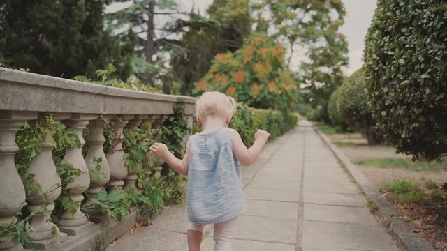 Small child girl walking outside at summer sunny day
