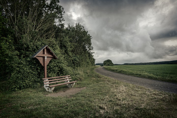 Bench and crucifix on the dirt road