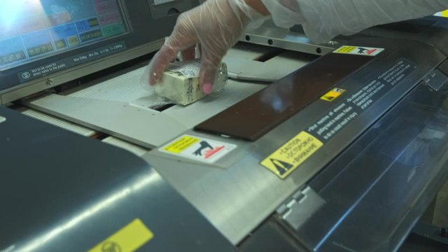 packaging products on the machine in the store. A piece of cheese is packed in cellophane.