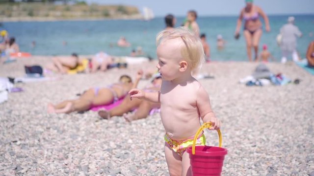 Little baby girl play with bucket on beach