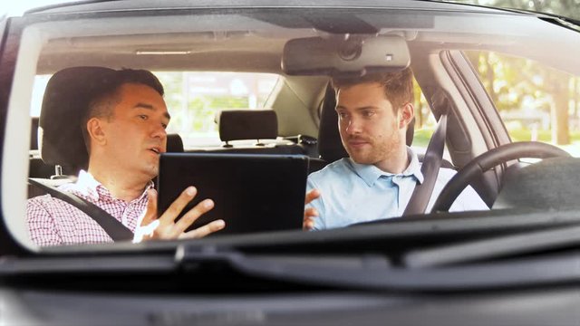 driver courses and people concept - man and driving school instructor with tablet computer talking in car