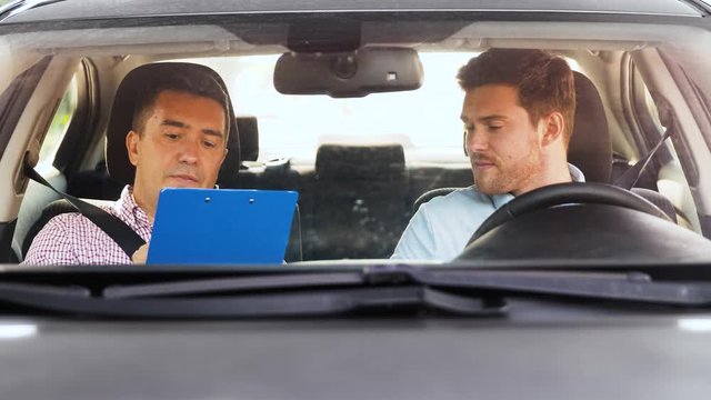driver courses and people concept - driving school instructor with clipboard talking to man failed exam in car