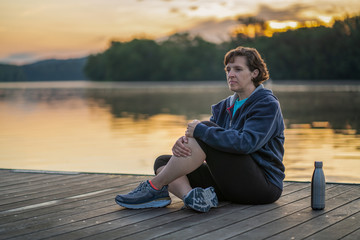 Older woman stretching in the early morning by a river