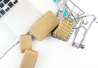 Miniature shopping cart and cardboard boxes spilled over laptop computer isolated on white - Powered by Adobe