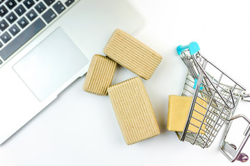 Miniature shopping cart and cardboard boxes spilled over laptop computer isolated on white - Powered by Adobe