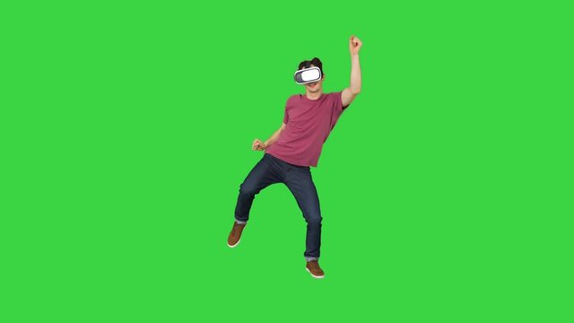 Advanced gamer in casual outfit playing dancing game in VG headset on a Green Screen, Chroma Key.