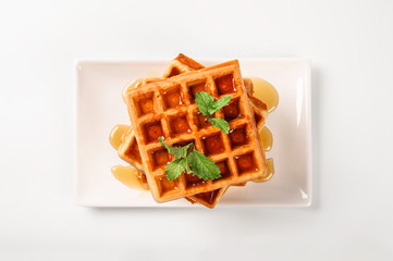 Fresh waffles with honey and mint on top  on white background.