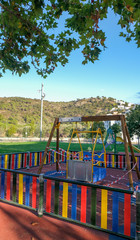 Swing pole for children with disabilities on wheelchair in the playground on clear blue sky and mountain background. Concept of caring for children with disabilities.