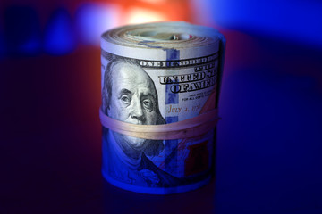 financial image of close up rolled and rubber banded American one hundred dollar bills pile on desk