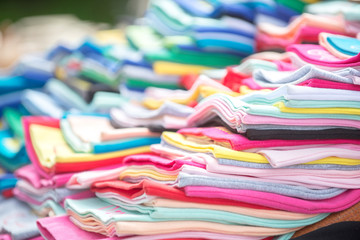 Multi-colored rainbow warm pastel fabrics are stacked on blurred background. The concept of a wide selection and sale, dry cleaning or laundry.