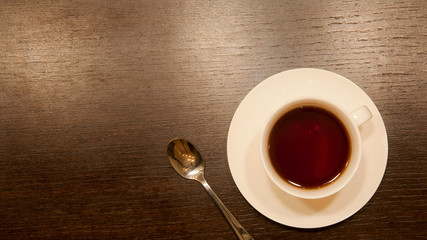 Cup of tea with a spoon on a brown wood table