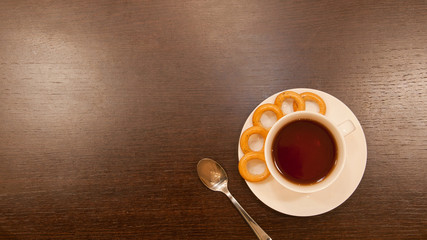Cup of tea with a spoon on a brown wood table
