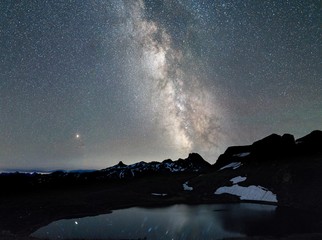 Beautiful shot of snowy mountain near a pond under a sky filled with stars