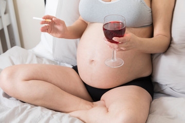 Pregnant woman smoking cigarette and drinking alcohol