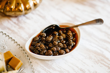 Traditional Siberian dessert - Jam of young pine cones. Selective focus. Jam of fir cones in a plate on the table.