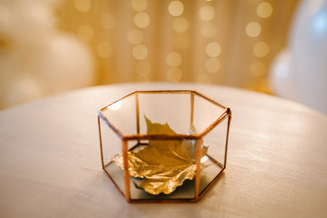 Fototapeta na wymiar Dry golden leaf in a metal box on the table. Gold wedding reception. Autumn style. Luxury elegant wedding decor for the ceremony.