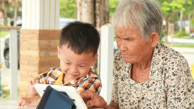 Grandmother lernning using tablet with grandson.
