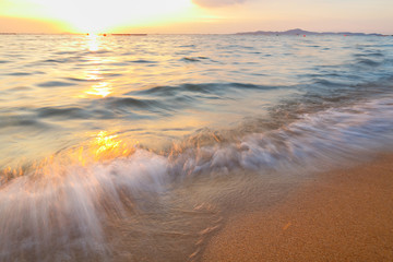 Fototapeta na wymiar Sunset on the beach, seeing sun dawning and smooth sea wave.