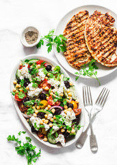Mediterranean style lunch table - Greek chickpeas salad and pork chops on light background, top view