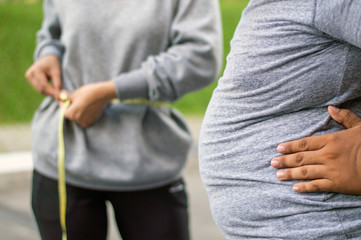 body part of fat man envy to skinny woman  at outdoor city park