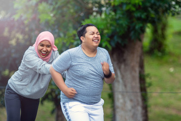 two people, with young Muslim women encouraging Asian male friends who are overweight to exercise...