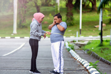 Two people, muslim woman and fat man, proportional and over weight, comparing themselves, by...
