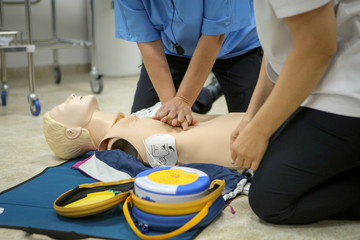 Woman medic demonstrates CPR methods on a plastic mannequin - obrazy, fototapety, plakaty
