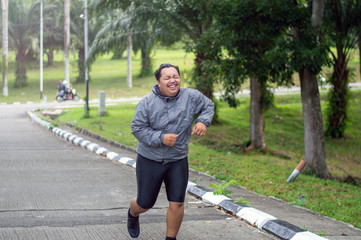 portrait of Fat man feeling tired to jogging in park. He need to lose weight