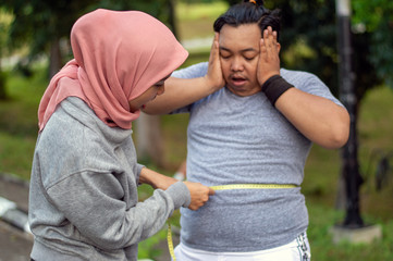 Two people, muslim woman and fat man, proportional and over weight, comparing themselves, by...