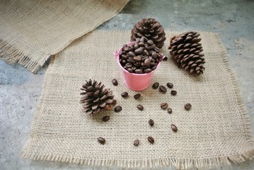 Roasted coffee beans in a pink zinc bucket on a sackcloth background.