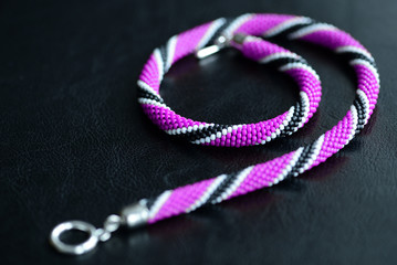 Beaded necklace purple, black and white colors on a dark background close up