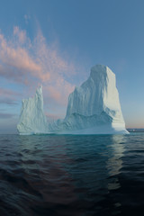 Fototapeta na wymiar Icebergs in front of the fishing town Ilulissat in Greenland. Nature and landscapes of Greenland. Travel on the vessel among ices. Phenomenon of global warming. Ices of unusual forms and colors. 