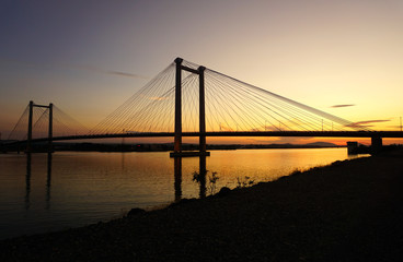 Fototapeta na wymiar suspension bridge over river at sunset