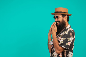 The concept of a happy man with a long beard wearing a hat, wearing a striped shirt showing a gesture on a blue background.