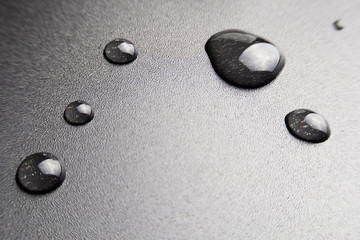 Fototapeta na wymiar Water drops on dark plastic surface background. copy space.