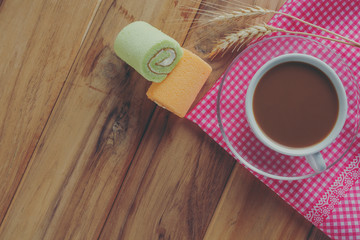 Coffee and bread placed on a pink patterned cloth on a brown wood floor.